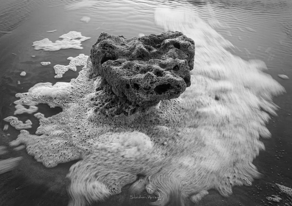 Rocher entouré par la marée montante sur la plage de Sotteville-sur-mer