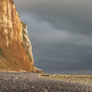 La falaise est éclairée par une lumière chaude alors que le ciel devient gris.